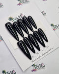 Ten black 2xl stiletto presson nail arranged on a white display card, photographed from above on a white background with Palm & Polish branding.
