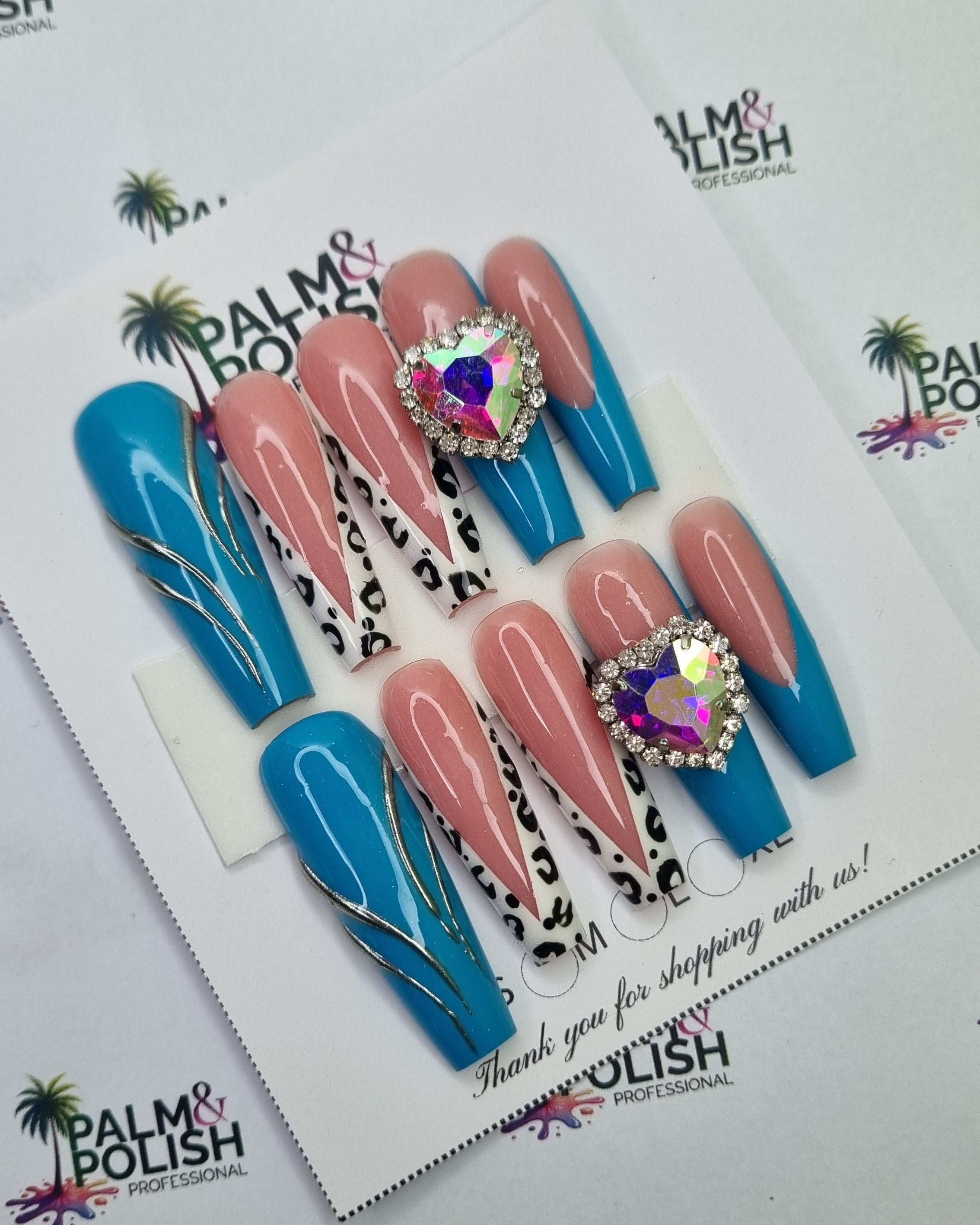 A set of acrylic press-on nails displayed on a white card, featuring pastel pink, bright blue, and leopard-print designs with rhinestone embellishments. The card is placed on a white background printed with the 'palm & Polish' brand logo.