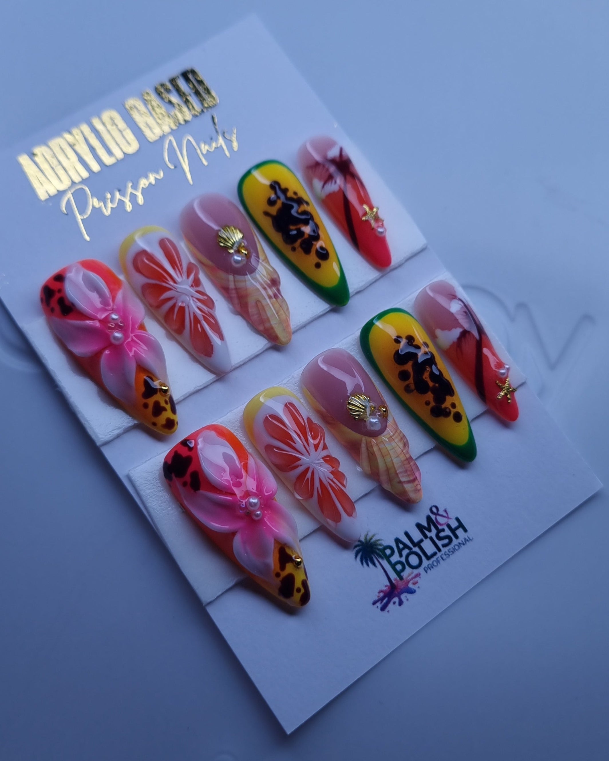 A set of colorful press-on nails displayed on a white card labeled 'Acrylic Press-On Nail vendor,' placed on a white plate.